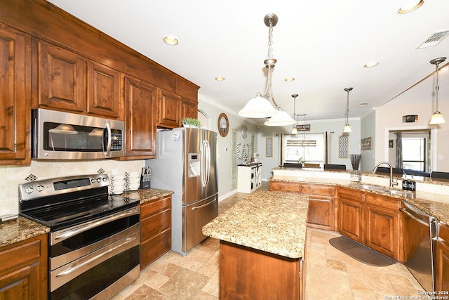 kitchen featuring a kitchen island, appliances with stainless steel finishes, pendant lighting, sink, and light stone countertops