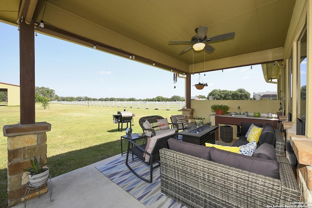 view of patio / terrace featuring a rural view, sink, an outdoor living space with a fire pit, and ceiling fan