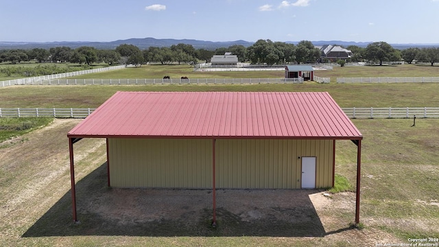 view of outdoor structure featuring a rural view, a mountain view, and a lawn