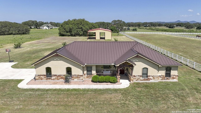 view of front of house featuring a mountain view, covered porch, a front yard, and a rural view