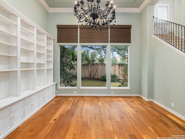 unfurnished dining area featuring crown molding, a wealth of natural light, a chandelier, and light hardwood / wood-style flooring
