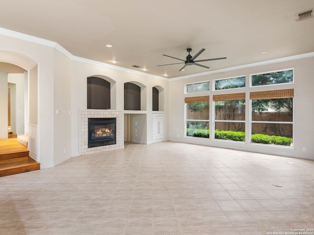unfurnished living room with a fireplace, ornamental molding, ceiling fan, and light tile patterned flooring