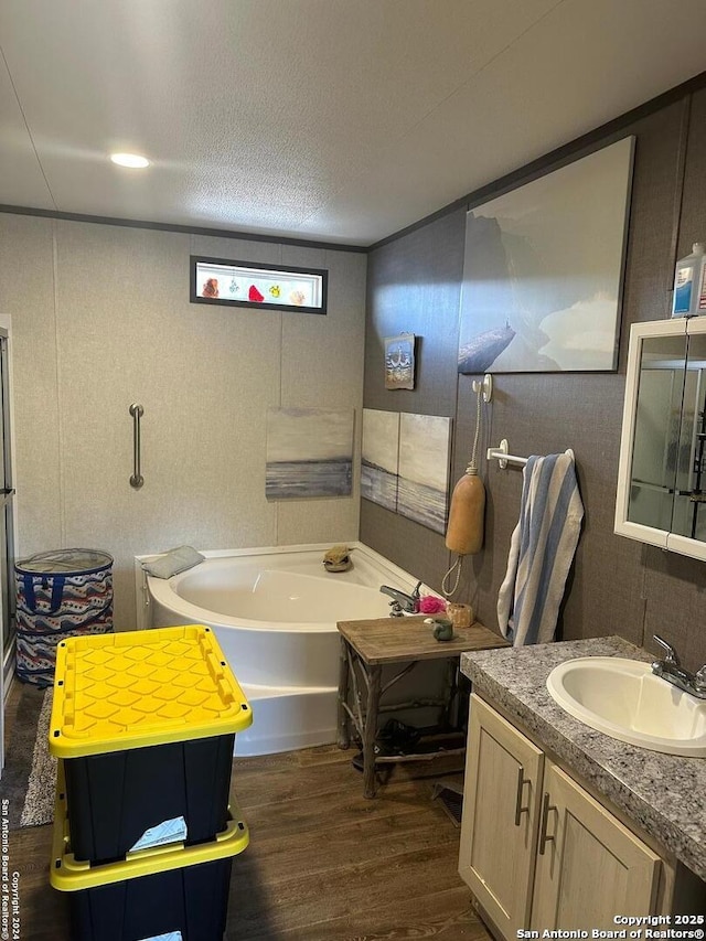 bathroom featuring a textured ceiling, hardwood / wood-style flooring, a bathtub, and vanity