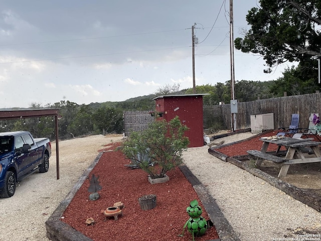 view of yard with an outdoor structure, fence, and a storage unit