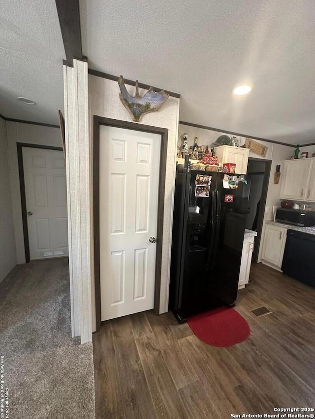 kitchen featuring black fridge, dark hardwood / wood-style floors, a textured ceiling, and white cabinets