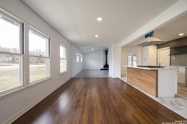 kitchen with stainless steel gas stovetop, white cabinetry, exhaust hood, and dark hardwood / wood-style flooring