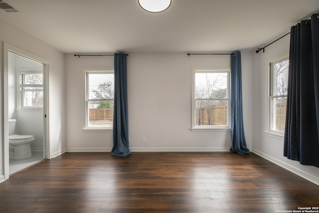 spare room featuring a healthy amount of sunlight and dark hardwood / wood-style flooring