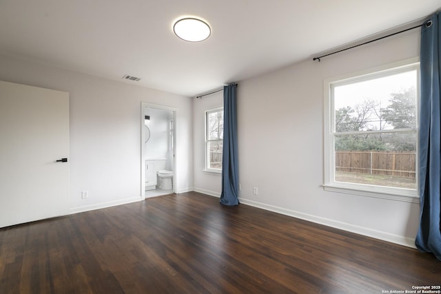 unfurnished bedroom featuring ensuite bath and dark hardwood / wood-style flooring