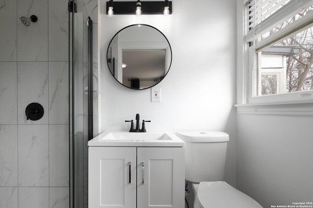 bathroom featuring vanity, a shower with shower door, and toilet