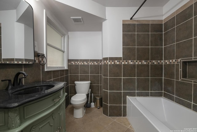 full bathroom with tile walls, vanity, toilet, tile patterned floors, and washtub / shower combination