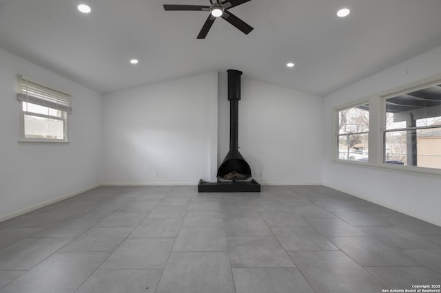 unfurnished living room with ceiling fan, light tile patterned floors, vaulted ceiling, and a wood stove