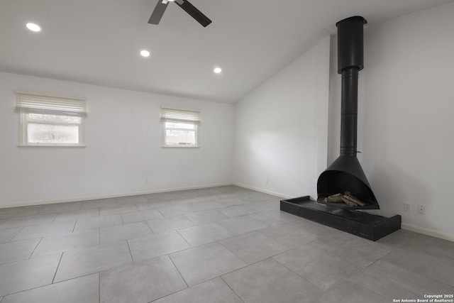 unfurnished living room featuring lofted ceiling, ceiling fan, and a wood stove