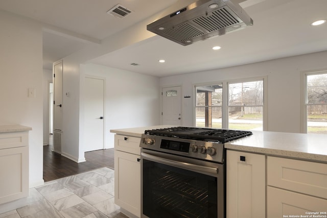 kitchen featuring white cabinetry, stainless steel gas range oven, and light stone counters