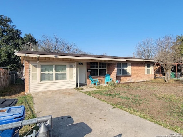 single story home featuring covered porch, fence, and brick siding