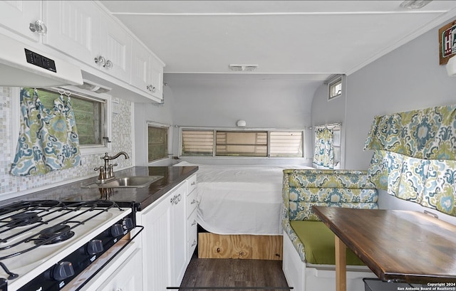 kitchen featuring sink, decorative backsplash, stovetop, and white cabinets