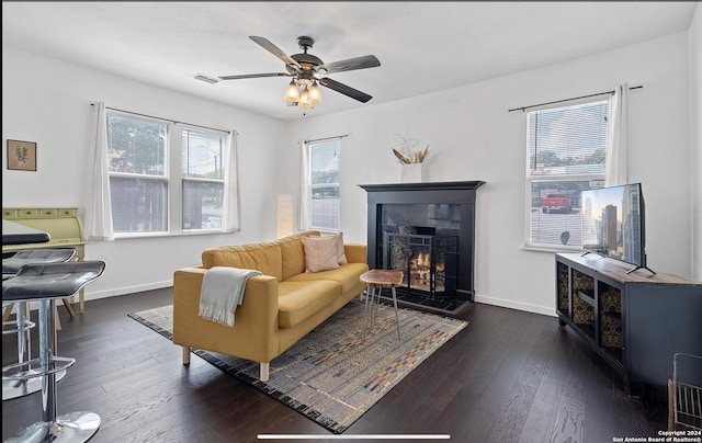 living room with a tiled fireplace, dark hardwood / wood-style floors, and ceiling fan