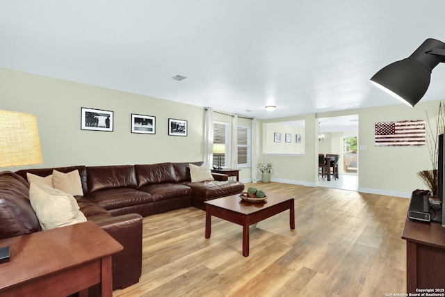 living area with baseboards, visible vents, and light wood-style floors