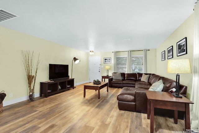 living area featuring light wood-type flooring, visible vents, and baseboards