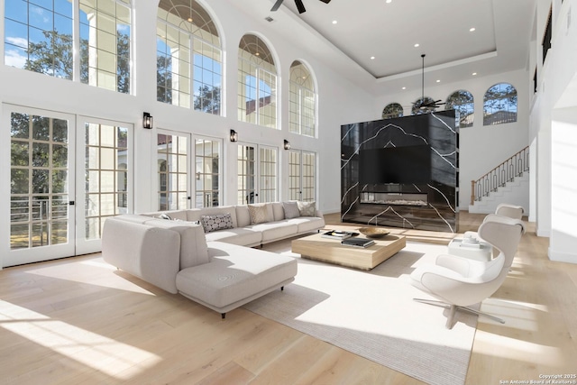 interior space with a raised ceiling, french doors, and ceiling fan