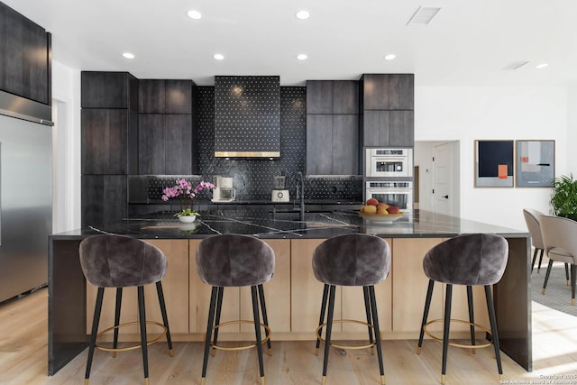 kitchen with light hardwood / wood-style flooring, stainless steel appliances, and a breakfast bar