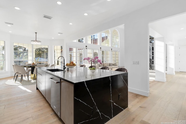 kitchen featuring decorative light fixtures, sink, stainless steel dishwasher, and a spacious island