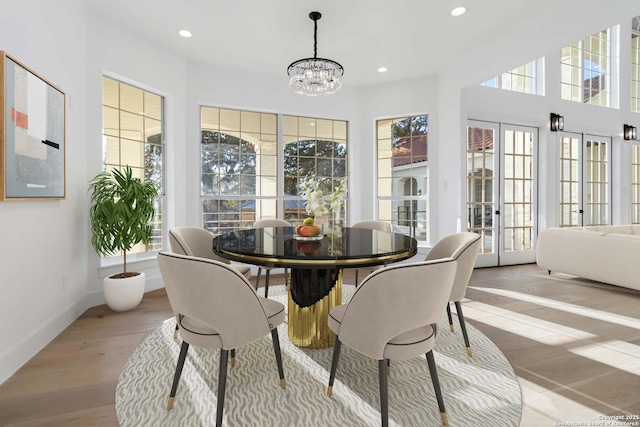 dining area featuring an inviting chandelier, light hardwood / wood-style floors, and french doors