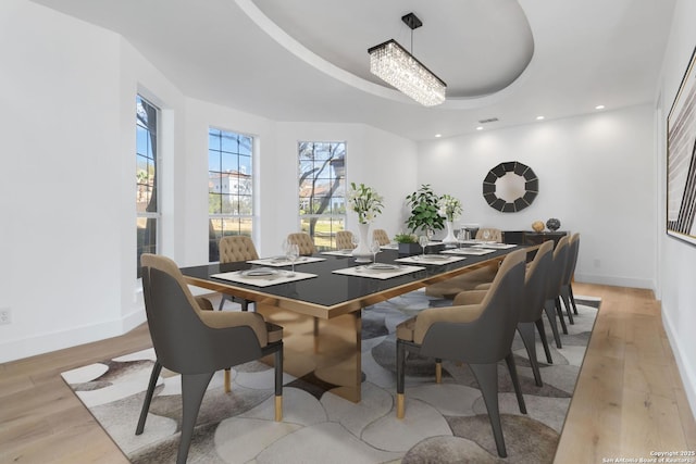 dining area with a tray ceiling and light hardwood / wood-style floors