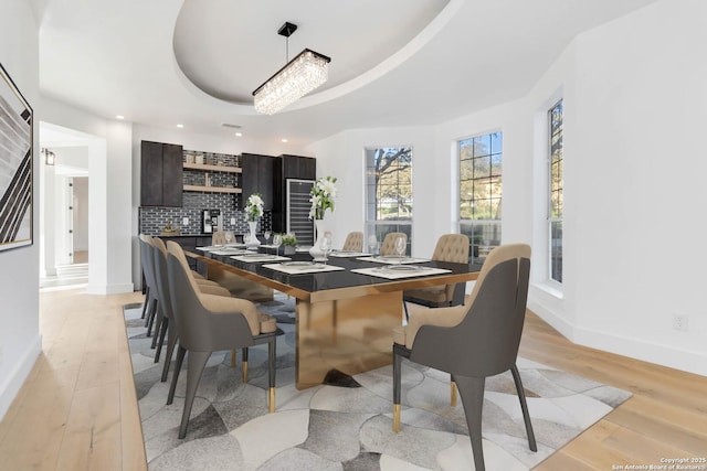 dining room with a raised ceiling and light hardwood / wood-style flooring