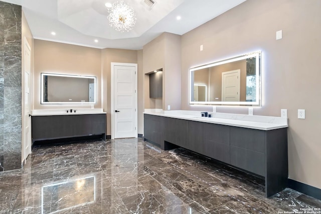 bathroom with vanity, a tray ceiling, and a chandelier