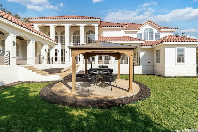 rear view of property with a gazebo, a patio area, and a lawn