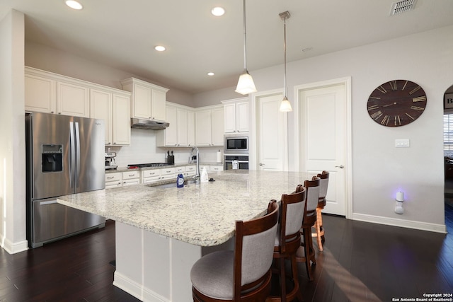 kitchen with white cabinetry, a center island with sink, appliances with stainless steel finishes, pendant lighting, and light stone countertops