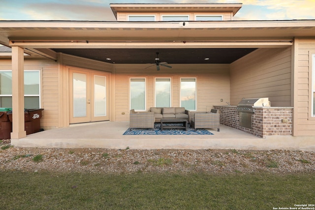 back house at dusk featuring french doors, an outdoor kitchen, ceiling fan, an outdoor hangout area, and a patio