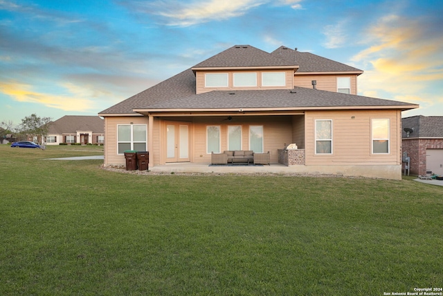 back house at dusk with a patio, outdoor lounge area, ceiling fan, and a lawn