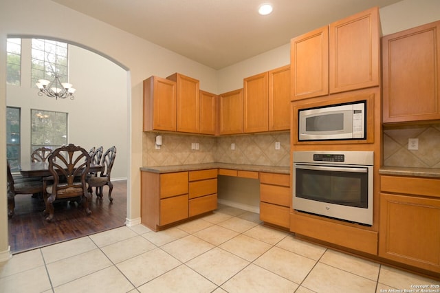 13906 Tahoe Vis, San Antonio, TX 78253 - kitchen with stainless steel oven, backsplash, light tile patterned flooring, a notable chandelier, and white microwave