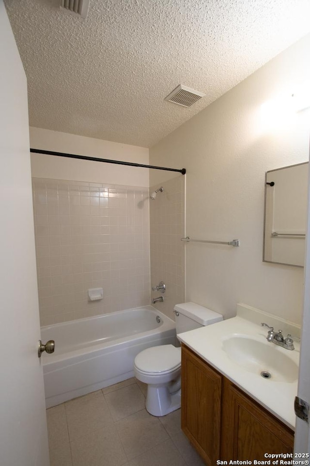 full bathroom featuring tiled shower / bath combo, vanity, toilet, tile patterned floors, and a textured ceiling