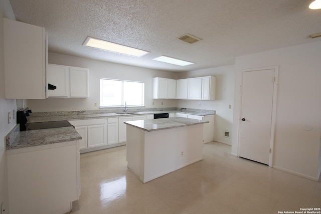 kitchen with sink, white cabinetry, a center island, electric range, and light stone countertops