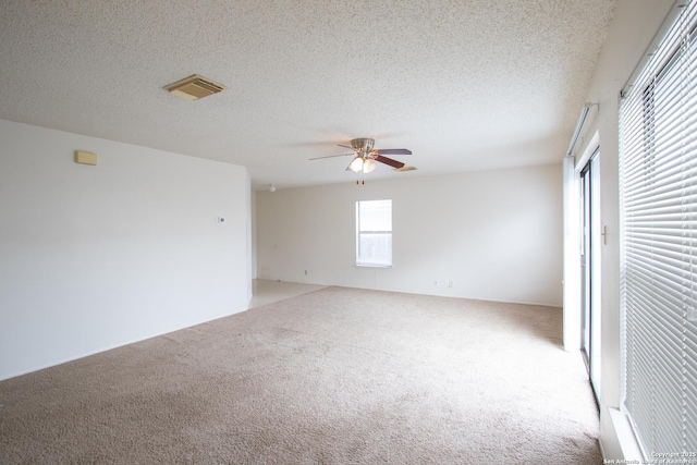 carpeted spare room featuring ceiling fan and a textured ceiling