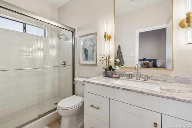 bathroom featuring vanity, toilet, and a shower with door