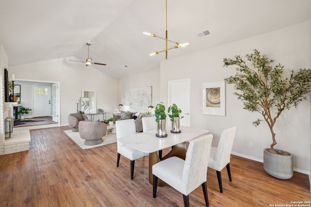 dining area featuring lofted ceiling, ceiling fan with notable chandelier, and light wood-type flooring