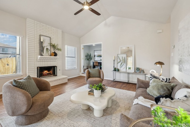 living room featuring hardwood / wood-style floors, a fireplace, high vaulted ceiling, and ceiling fan