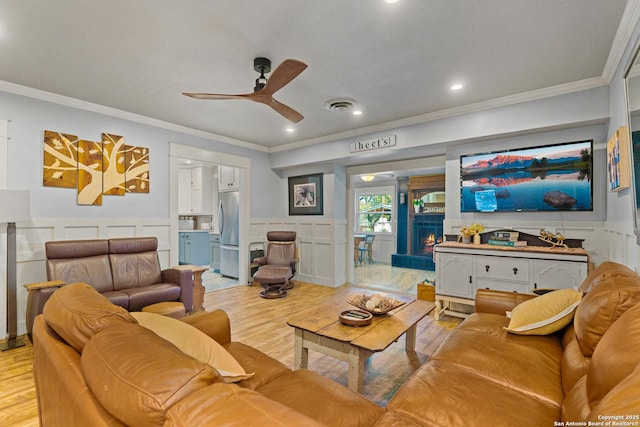 living room featuring light hardwood / wood-style flooring, ornamental molding, and ceiling fan