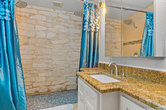 bathroom with vanity and tiled shower