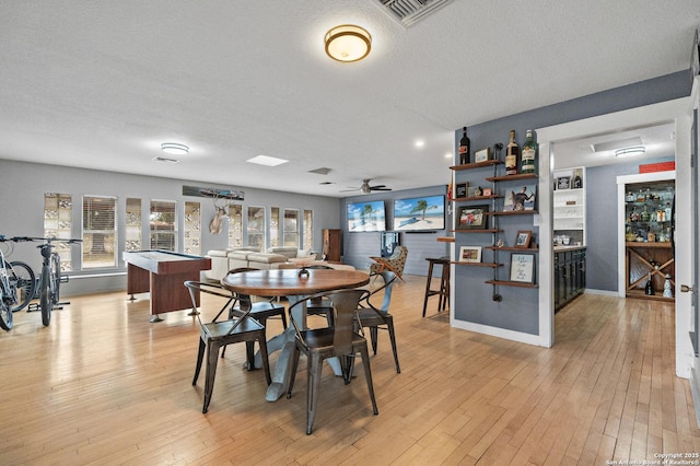 dining area featuring ceiling fan, light hardwood / wood-style flooring, and a textured ceiling