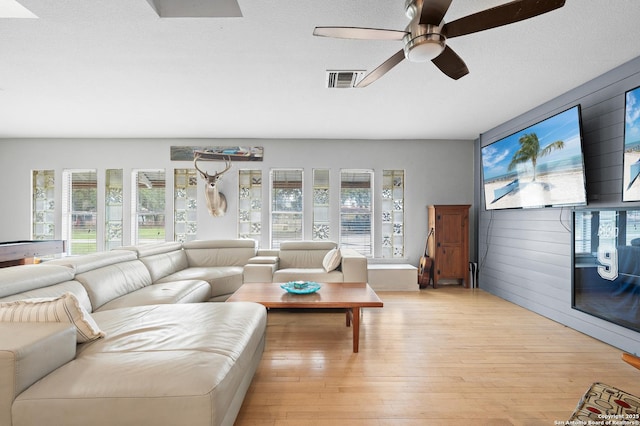 living room featuring ceiling fan, a textured ceiling, and light wood-type flooring