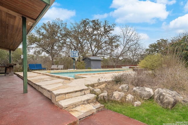 view of swimming pool with a patio and a storage unit