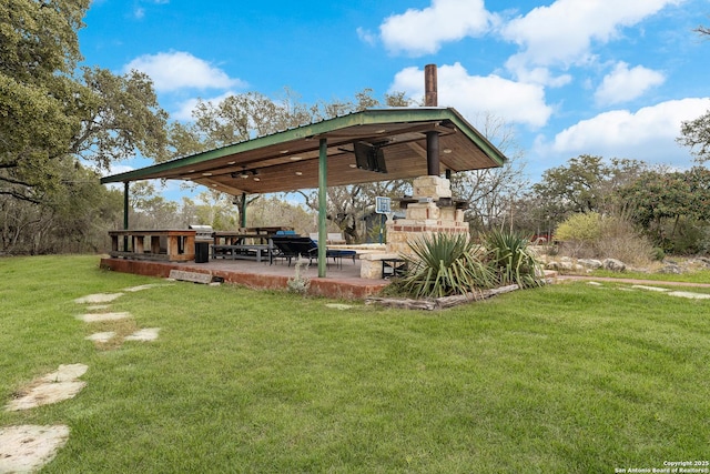 view of yard with an outdoor fireplace and a patio