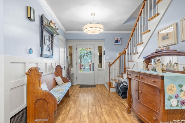 entrance foyer with ornamental molding and light hardwood / wood-style flooring