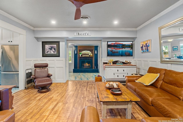 living room with crown molding, a fireplace, and light hardwood / wood-style floors