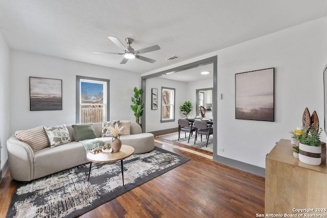 living room featuring dark wood-type flooring and ceiling fan