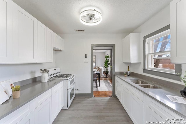 kitchen with sink, white cabinetry, a textured ceiling, double oven range, and light hardwood / wood-style floors